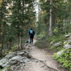 11 things to do on colorado vacation blog post main image - girl hiking on a mountain trail in the woods